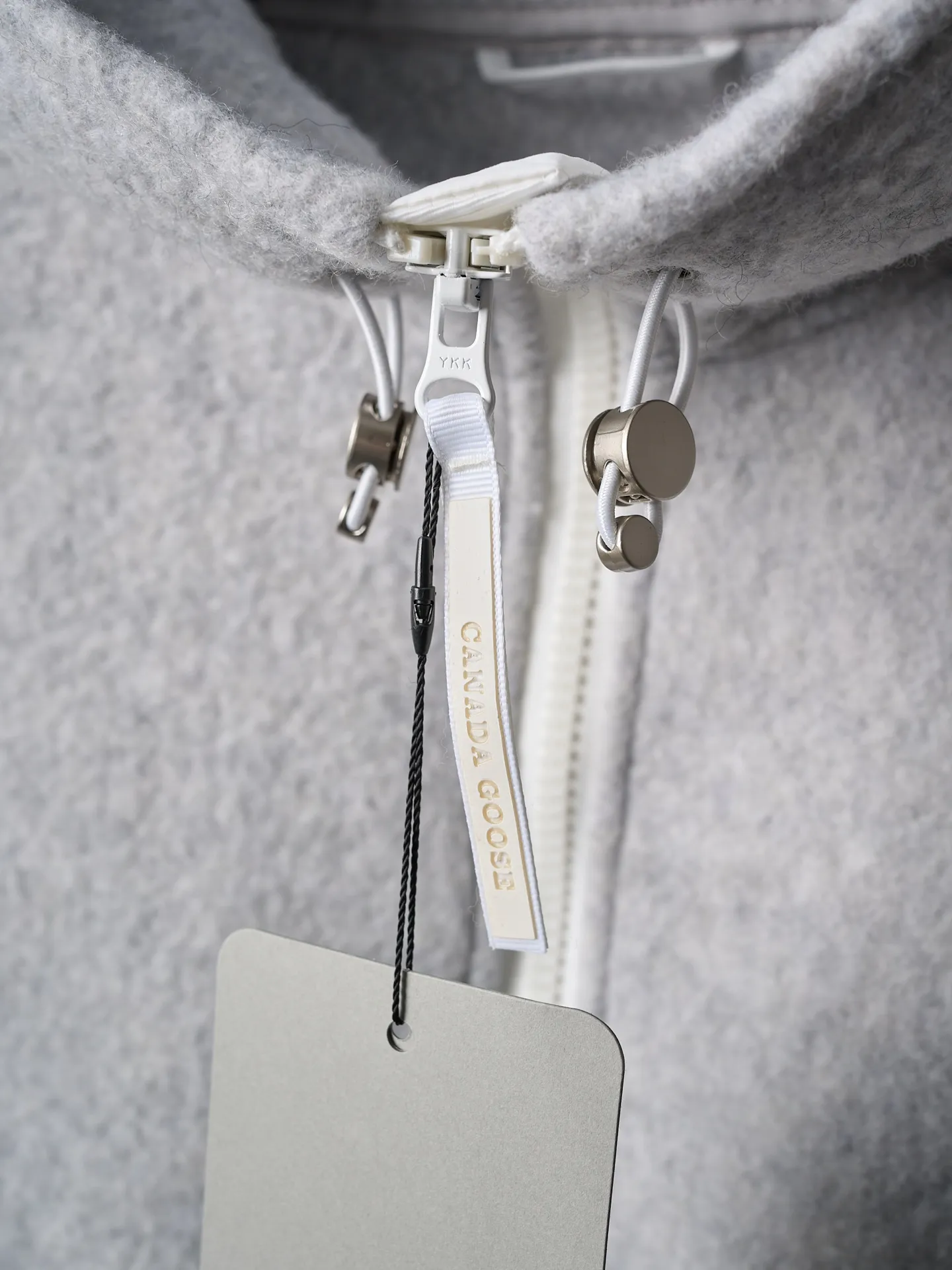 P780 Actual hanging auction] CANADA GOOSE/Canada Goose Chilliwack white label wool fleece hooded jacket [Ready stock] S M L XL Fabric selection: Wool fleece fabric made of wool as the main body and a very small amount of spandex and polyester fiber blended. Wool is a core natural ingredient that provides unparalleled temperature regulation, antibacterial and anti-odor properties and a skin-friendly feel. The feeding of a small amount of spandex gives the fabric a certain degree of four-way elasticity, making it non-restrictive during daily activities. As the basis of fleece's structure, polyester fiber enhances the fabric's durability, wrinkle resistance and quick-drying properties. It contributes to the loft of the fleece and provides functions such as trapping air.  Detail 1: The sleeves and hem are closed with 2×2 ribbing. Its strong elasticity can closely fit wrists and waists of different thicknesses, forming an effective 'seal' to prevent cold wind from blowing back. It can still maintain its original shape after repeated stretching and use, and is not easy to loose and deform. And the ribbed cuffs can convey a sense of design and enhance the visual beauty.  Detail 2: The combination of hood design and elastic buckle improves warmth and windproof performance when wearing.